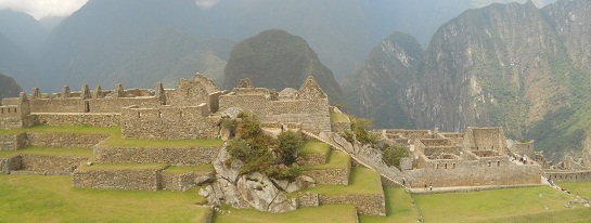 Machu Picchu: Sicht vom Meditationszimmer auf den Zentralplatz mit den Arbeitshusern, mit der grossen Mauer, dem Spiegeltempel und den Putucusi-Berg, grosses Panoramafoto